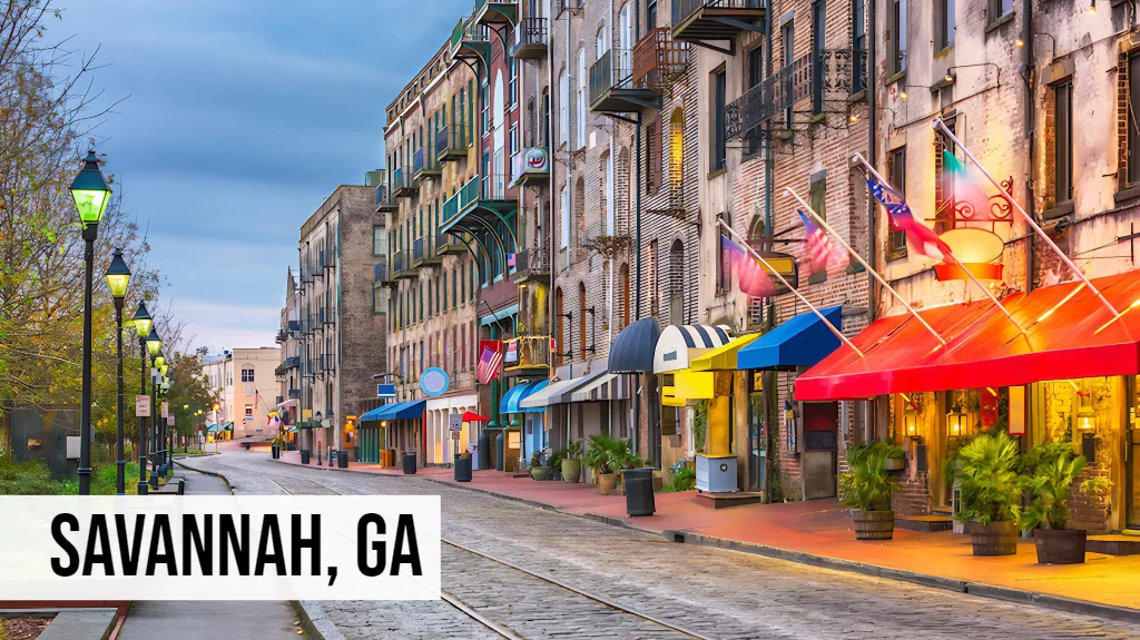 Savannah, Georgia historic downtown street view with colorful storefronts, balconies, cobblestone street, and trees
