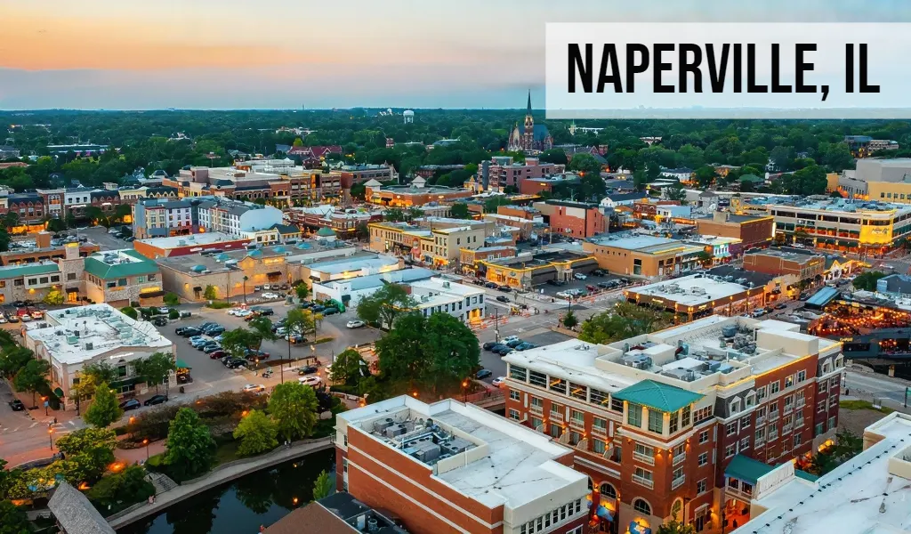 Naperville, Illinois downtown skyline with riverwalk, mixed-use buildings, and surrounding city area