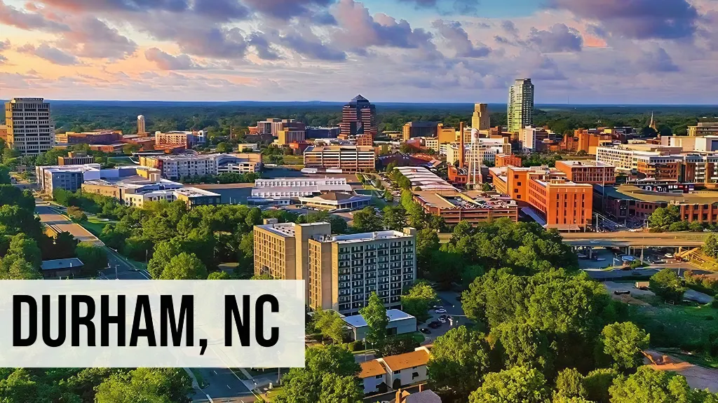 Durham, North Carolina aerial view of downtown with mixed-use buildings, streets, green space, and surrounding city