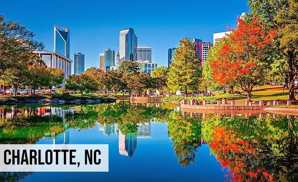 Charlotte, North Carolina city skyline view with park, trees, reflective water feature, and surrounding urban area