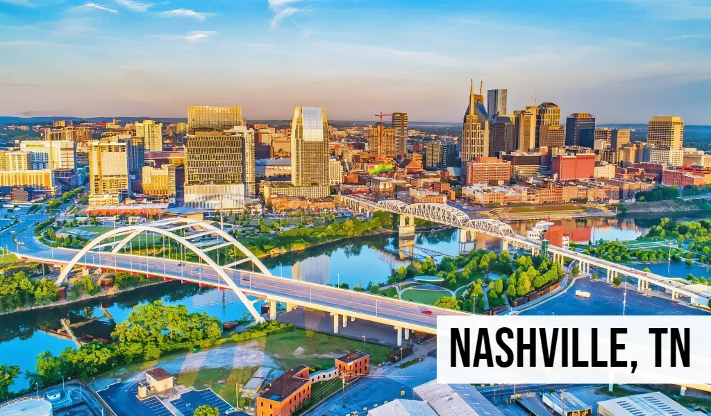 Sell My Land Tennessee – Nashville, TN Nashville, Tennessee aerial skyline view featuring downtown buildings, river crossings, green riverfront space, and surrounding urban development