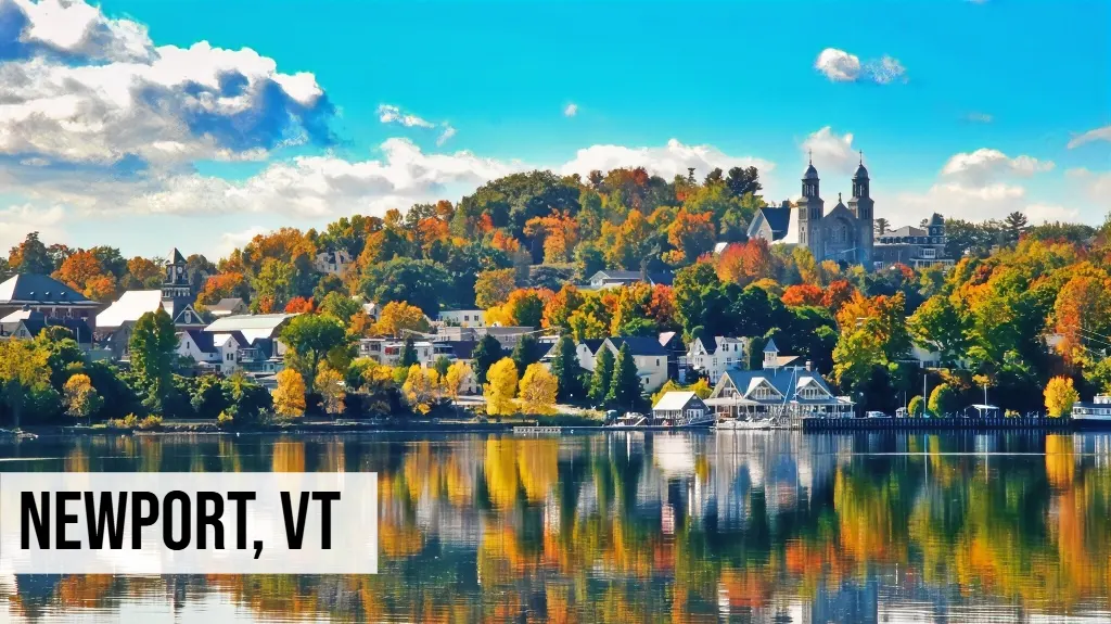 Newport, Vermont lakeside town view with waterfront buildings, reflections on water, trees, and surrounding hills