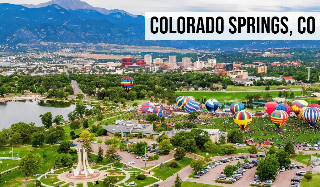 Colorado Springs, Colorado city view with downtown buildings, park area, hot air balloons, and mountains in the background