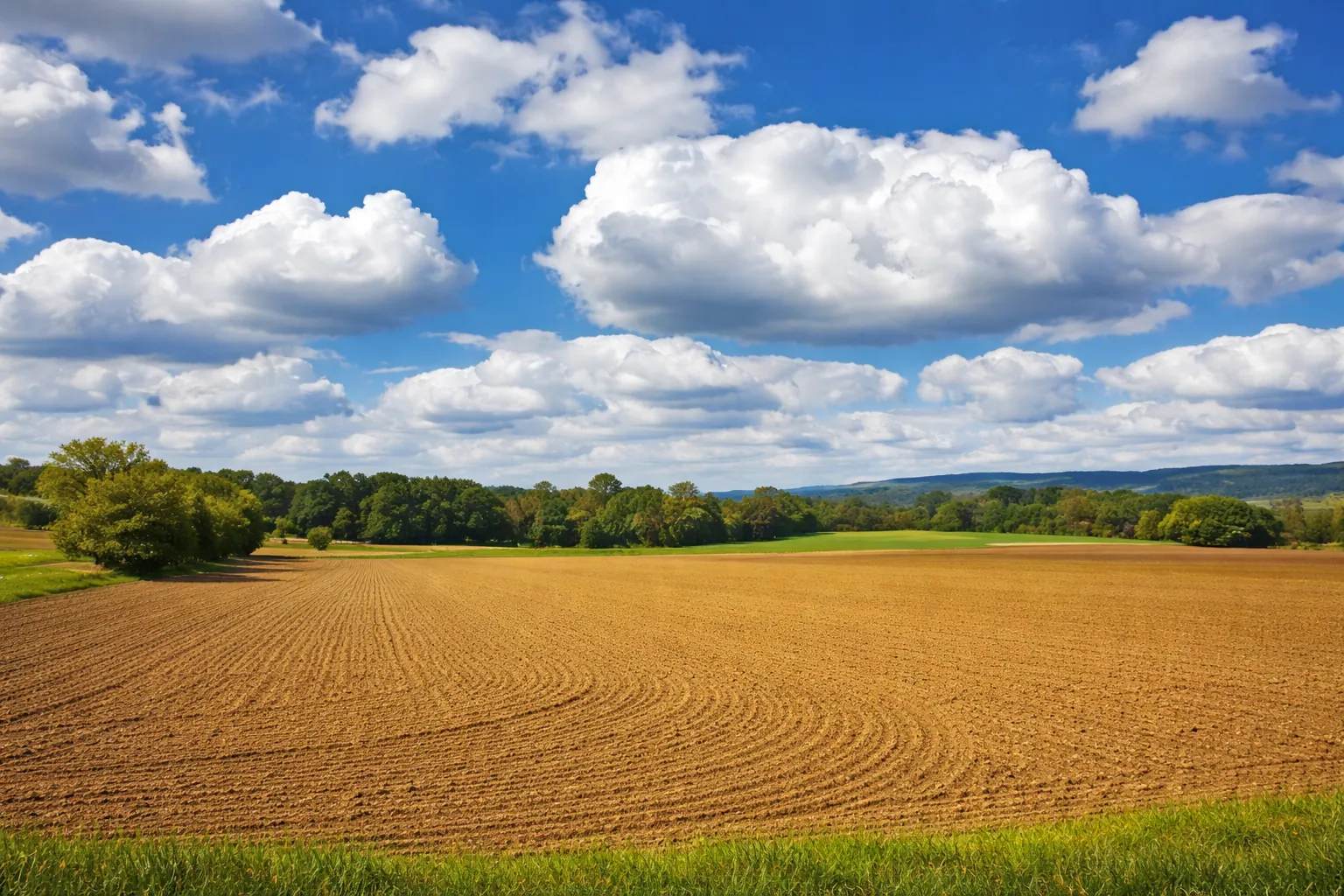 Aerial View of Farming Land in Iowa Iowa countryside with open farmland and dramatic clouds stretching across a bright blue sky.
